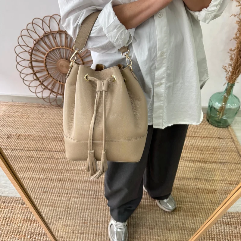 Bolso bucket piel taupe grande pompón iniciales bordadas
