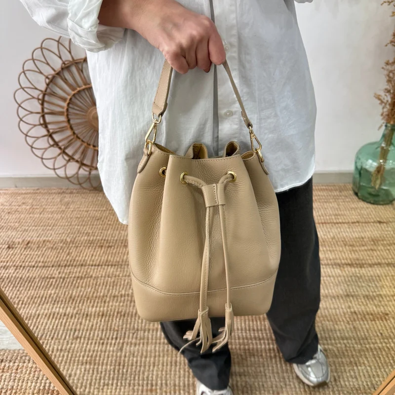 Bolso bucket piel taupe grande pompón iniciales bordadas