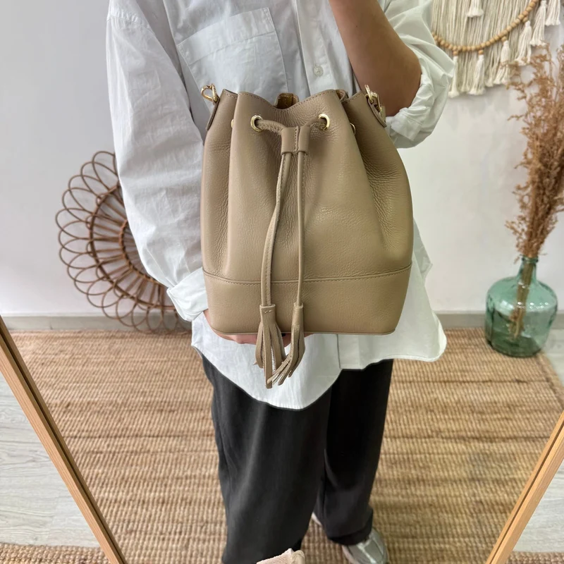 Bolso bucket piel taupe grande pompón iniciales bordadas