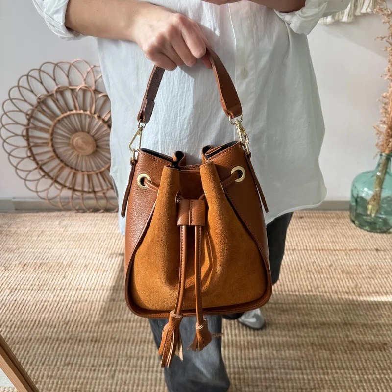 Bolso bucket combinado serraje y piel camel pompón iniciales bordadas