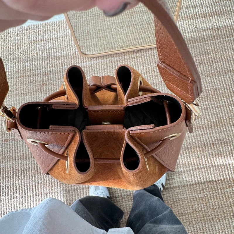 Bolso bucket combinado serraje y piel camel pompón iniciales bordadas