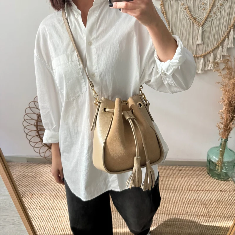 Bolso bucket combinado serraje y piel taupe pompón iniciales bordadas