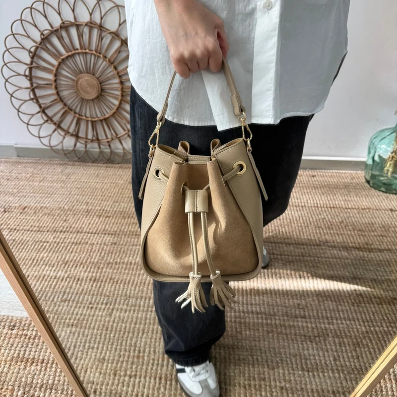 Bolso bucket combinado serraje y piel taupe pompón iniciales bordadas