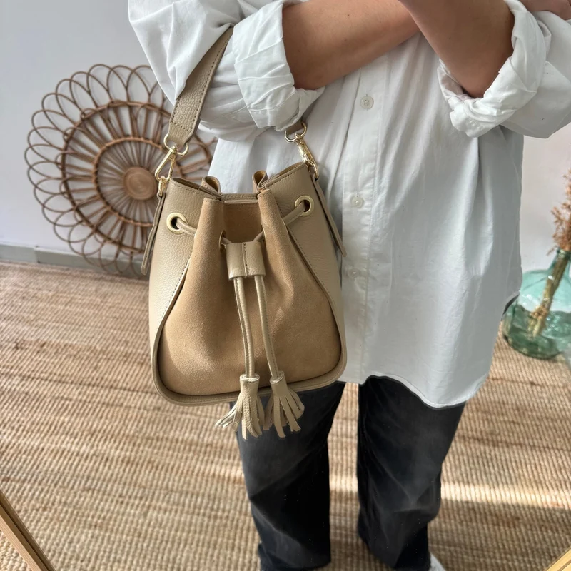 Bolso bucket combinado serraje y piel taupe pompón iniciales bordadas