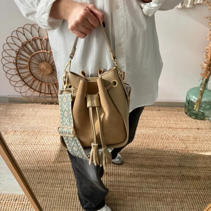 Bolso bucket combinado serraje y piel taupe pompón iniciales bordadas