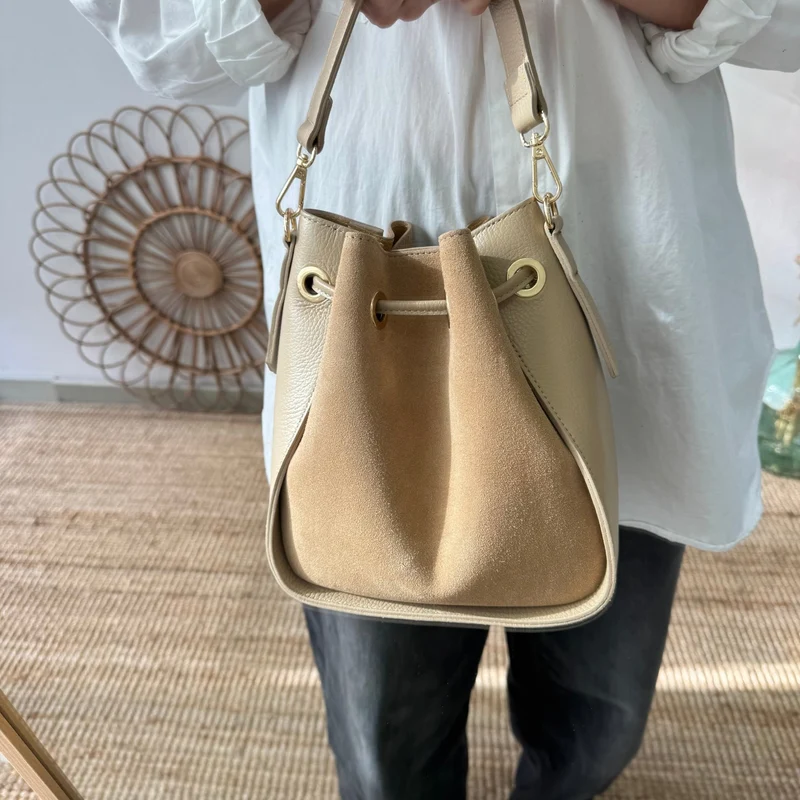 Bolso bucket combinado serraje y piel taupe pompón iniciales bordadas