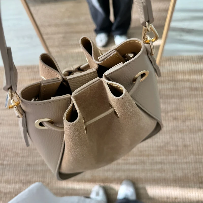 Bolso bucket combinado serraje y piel taupe pompón iniciales bordadas