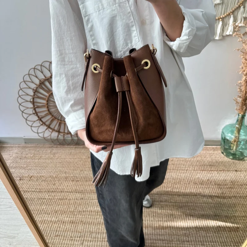 Bolso bucket combinado serraje y piel marrón pompón iniciales bordadas