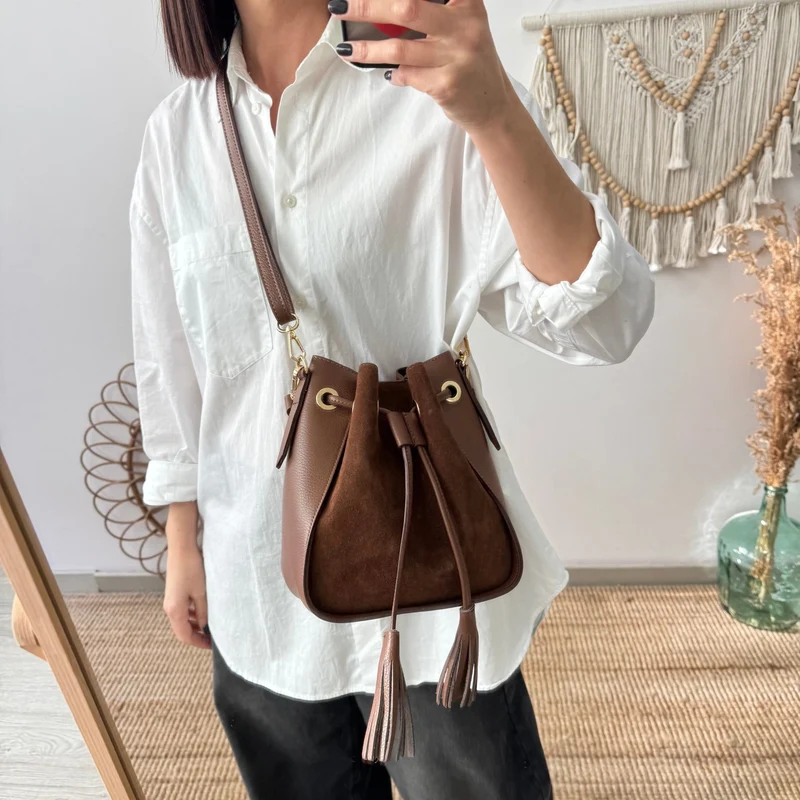 Bolso bucket combinado serraje y piel marrón pompón iniciales bordadas