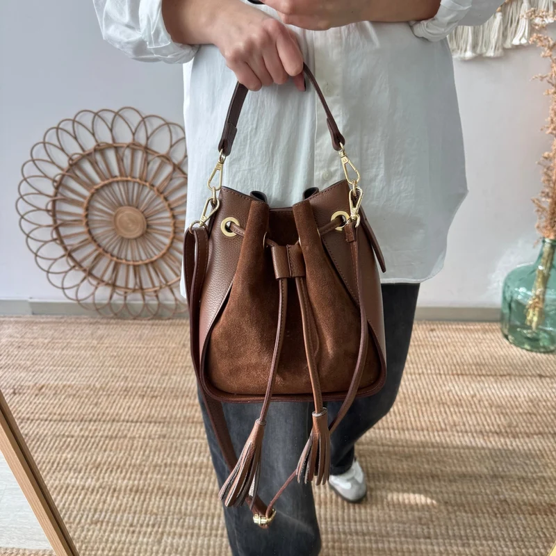 Bolso bucket combinado serraje y piel marrón pompón iniciales bordadas