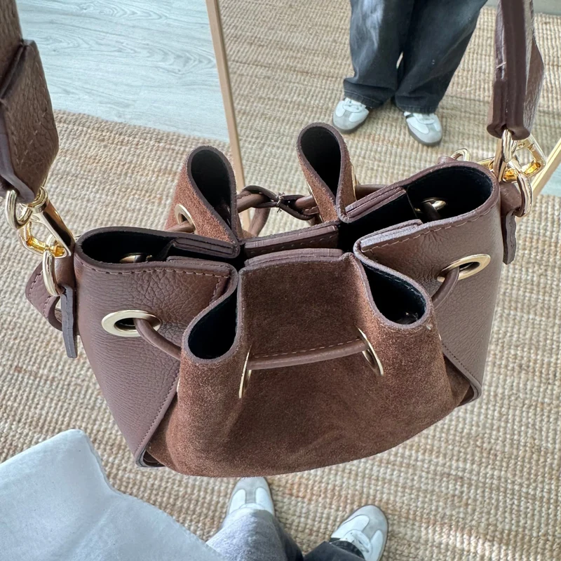 Bolso bucket combinado serraje y piel marrón pompón iniciales bordadas
