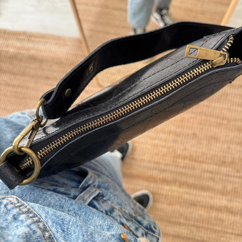 Bandolera ovalada piel tachuelas negra iniciales bordadas herrajes cobre
