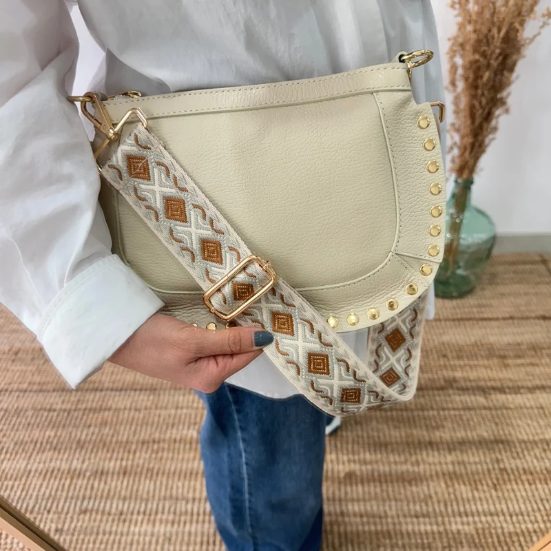 Bandolera ovalada piel tachuelas beige iniciales bordadas