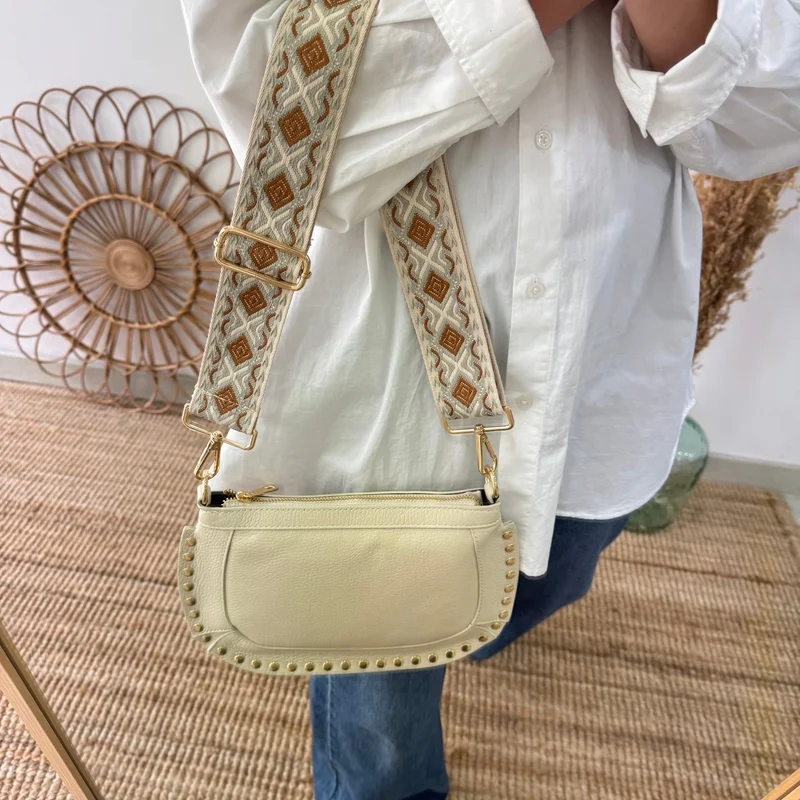 Bandolera ovalada piel tachuelas beige iniciales bordadas