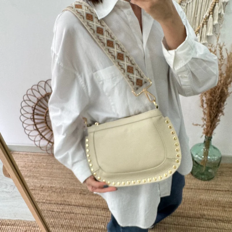 Bandolera ovalada piel tachuelas beige iniciales bordadas