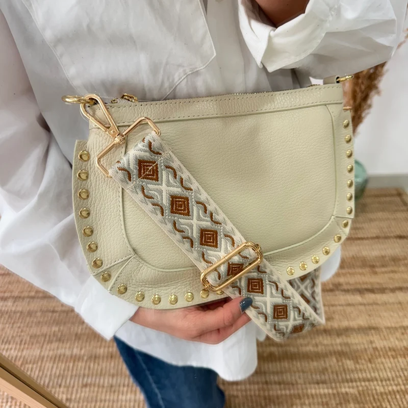 Bandolera ovalada piel tachuelas beige iniciales bordadas