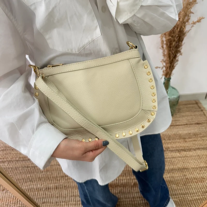 Bandolera ovalada piel tachuelas beige iniciales bordadas