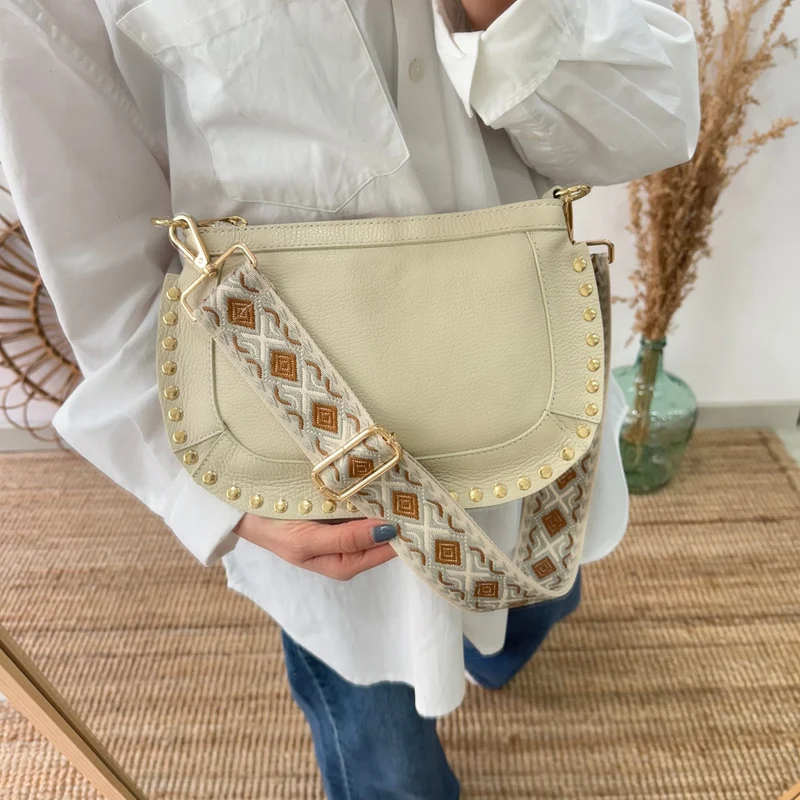 Bandolera ovalada piel tachuelas beige iniciales bordadas