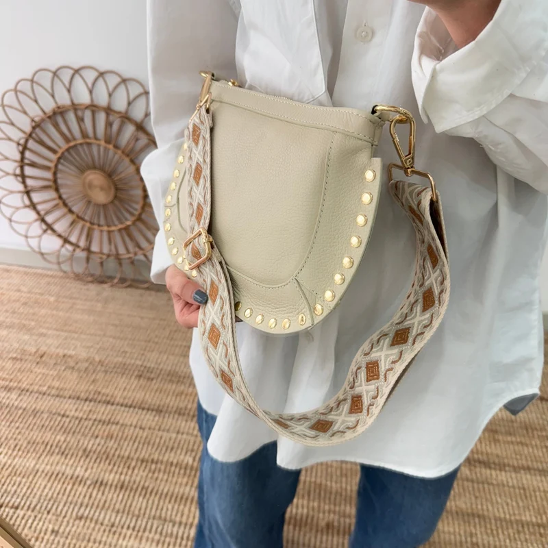 Bandolera ovalada piel tachuelas beige iniciales bordadas