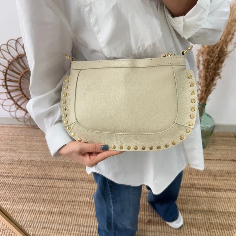 Bandolera ovalada piel tachuelas beige iniciales bordadas