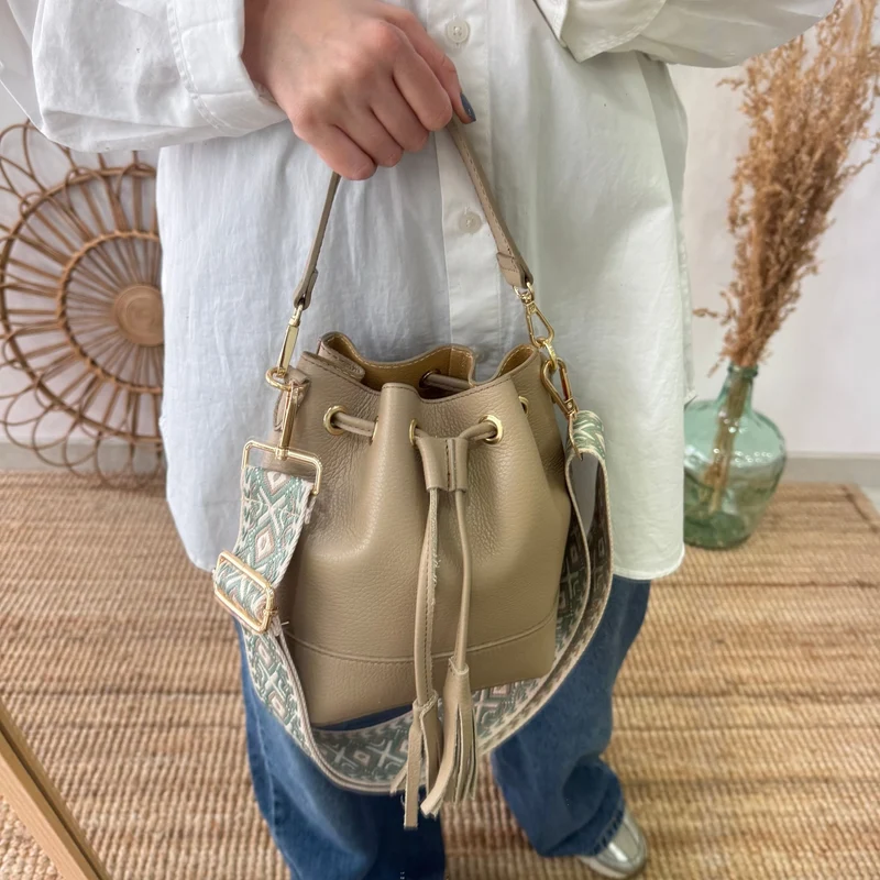 Bolso bucket piel taupe pompón iniciales bordadas