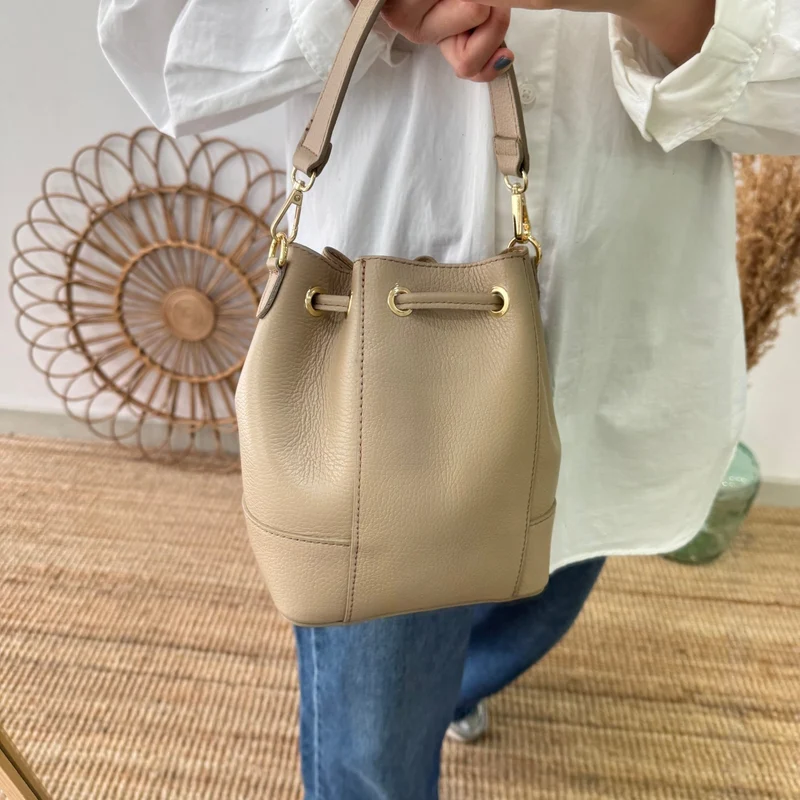 Bolso bucket piel taupe pompón iniciales bordadas