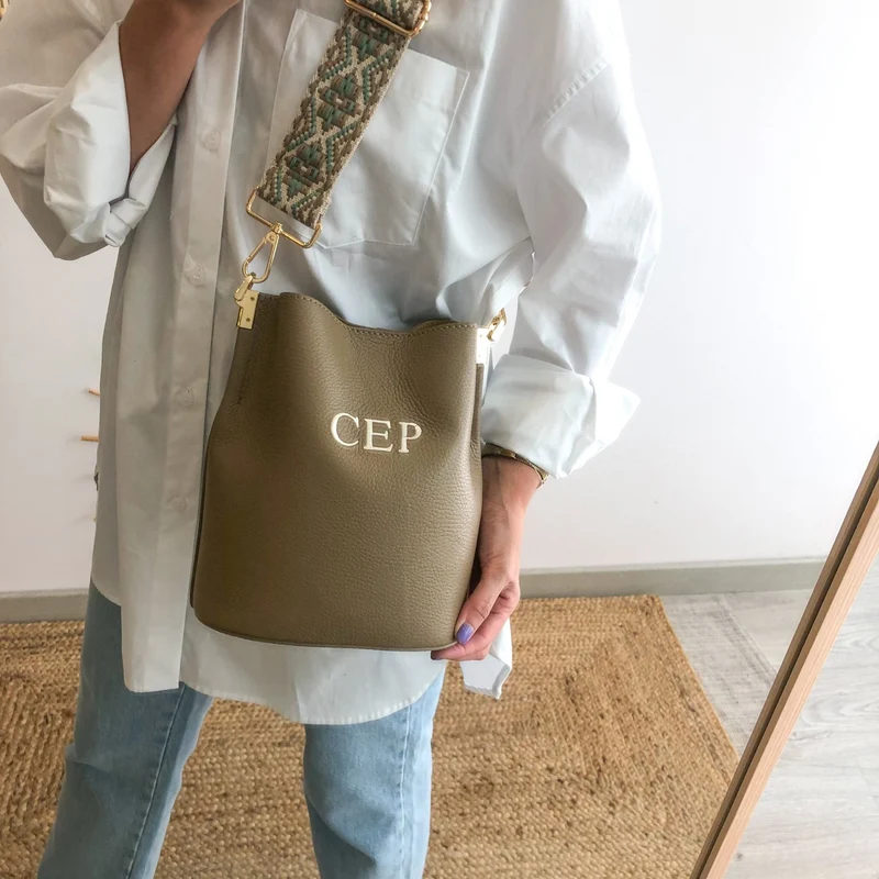Bolso bucket piel taupe cadena dorada iniciales bordadas