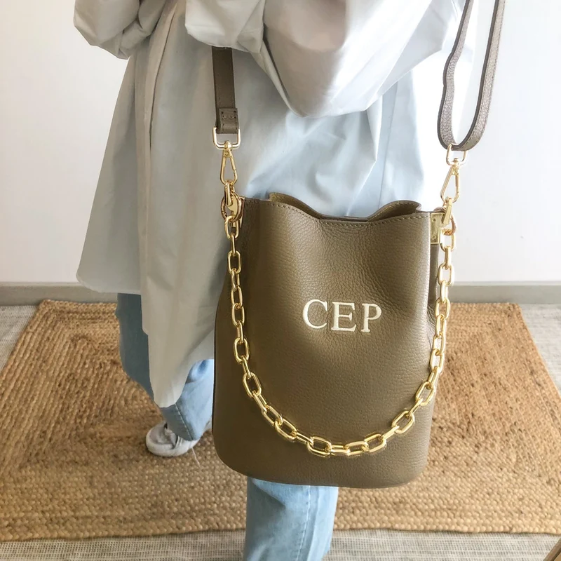 Bolso bucket piel taupe cadena dorada iniciales bordadas