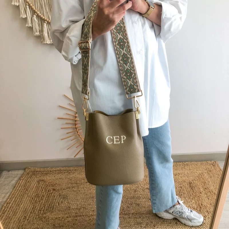 Bolso bucket piel taupe cadena dorada iniciales bordadas